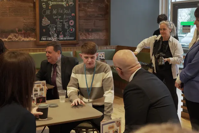 Joshua Adams of JADAMSTUTOR talking with guests around a café table at an event
